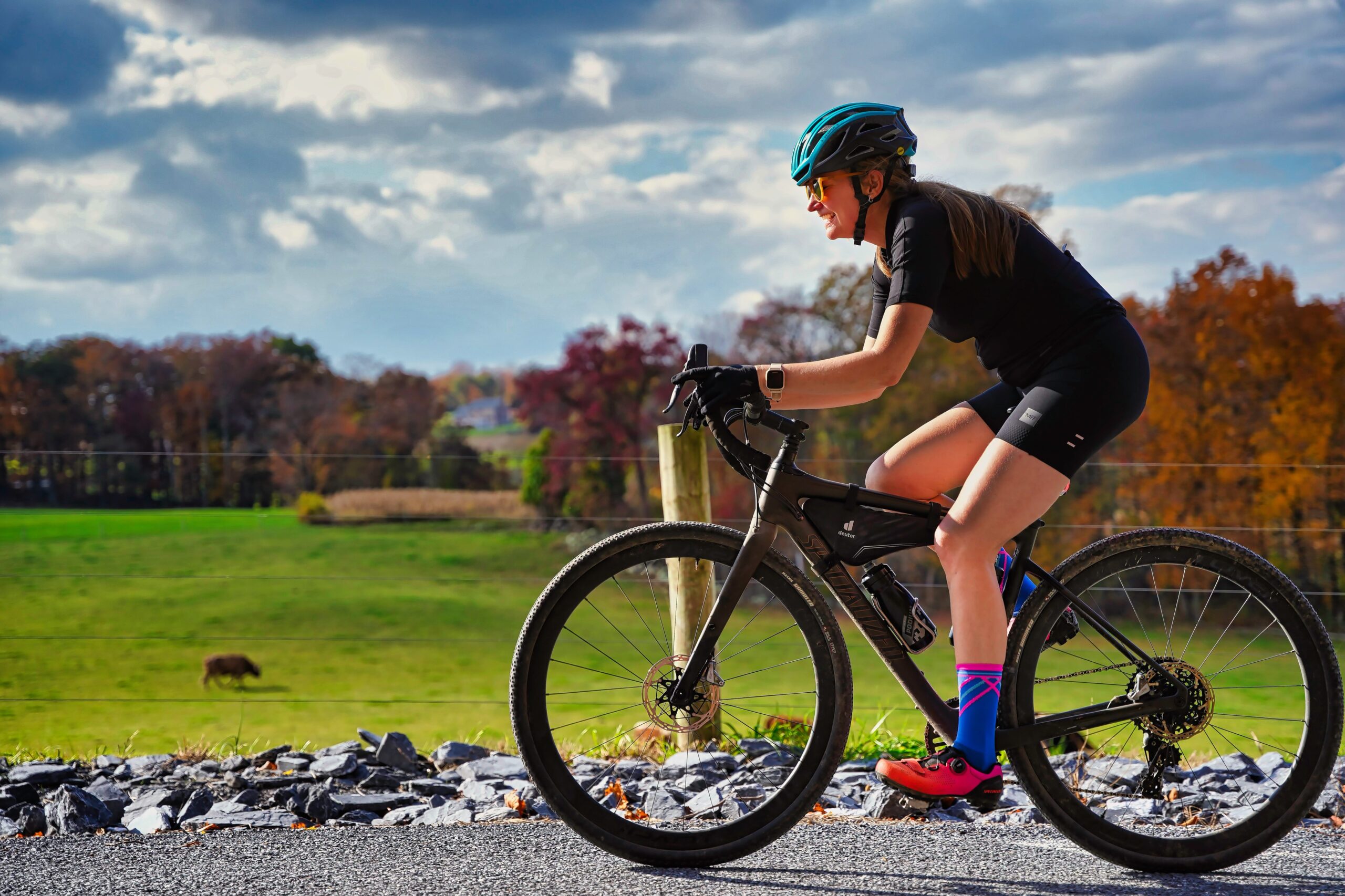 Woman cycling outdoors on a road bike through countryside scenery — outdoor cycling burns up to 850 calories per hour and is a low-impact fat burning exercise perfect for women of all fitness levels