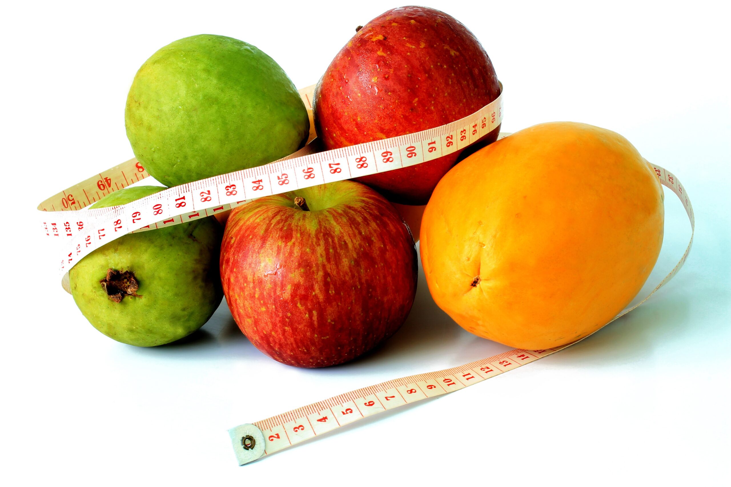 Fresh fruits including apples, pear and orange wrapped with a measuring tape — combining fat burning exercise with a healthy balanced diet is the most effective approach to sustainable weight loss for women